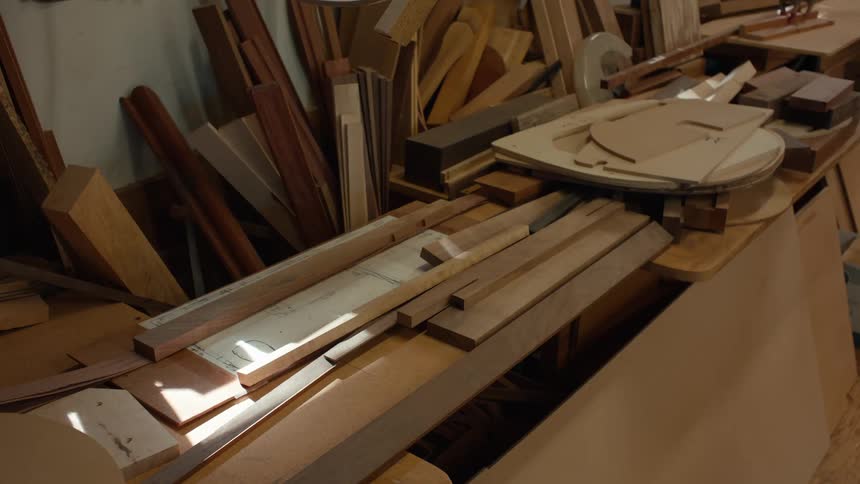 A workshop table cluttered with various pieces of wood and materials for carpentry