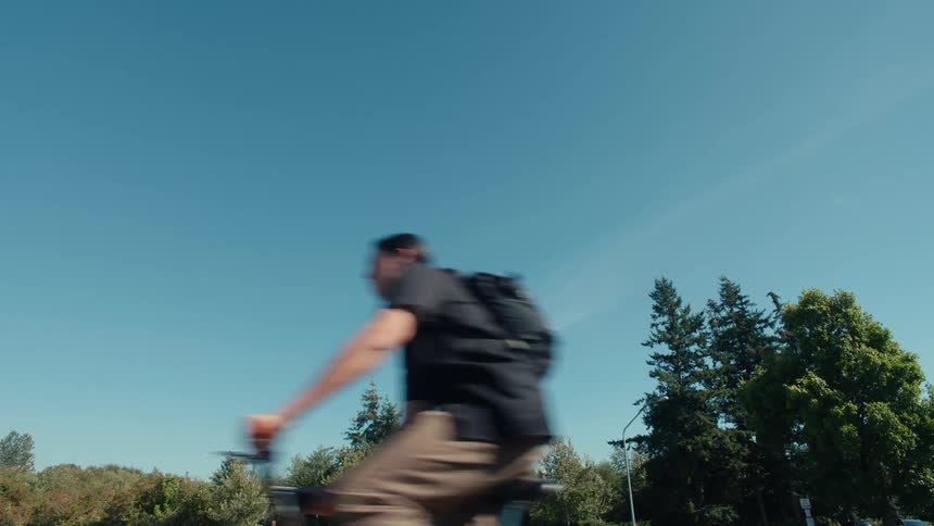 A person drives a bicycle under a clear blue sky