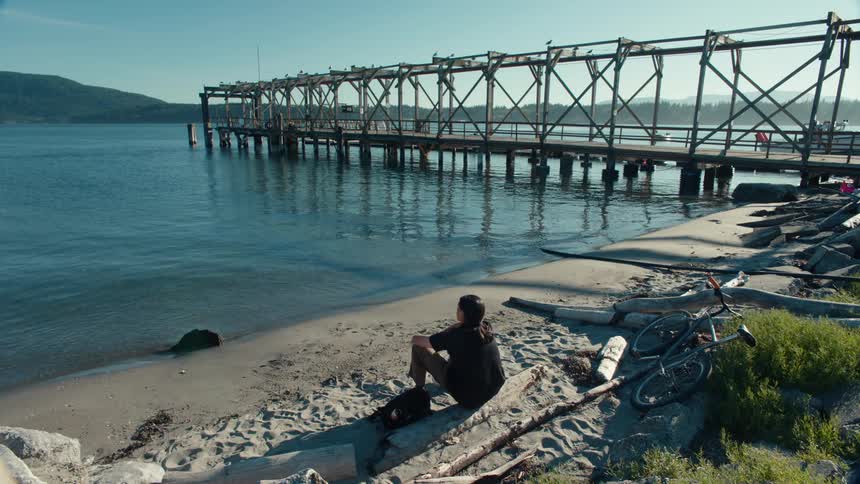 A man is sitting on the shore of the lake
