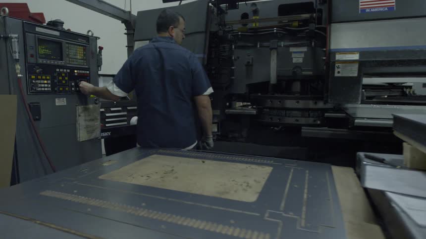 A factory worker adjusts a knob on a machine