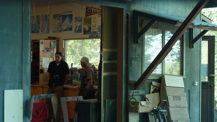 Young man talking to a carpenter in an indoor space