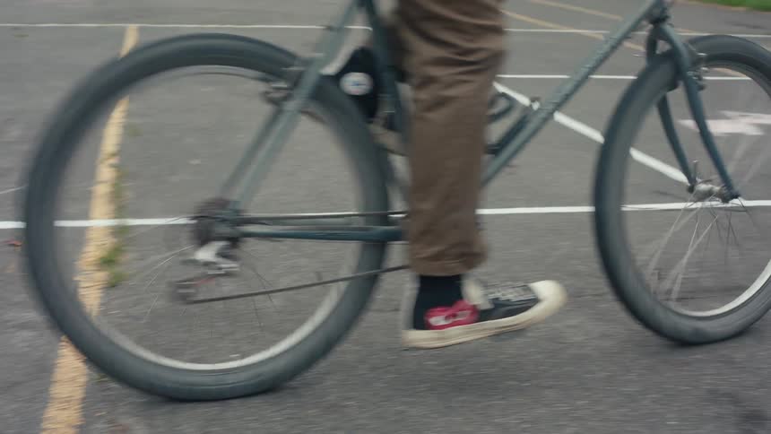 Person riding a bike in a circle in an empty parking lot