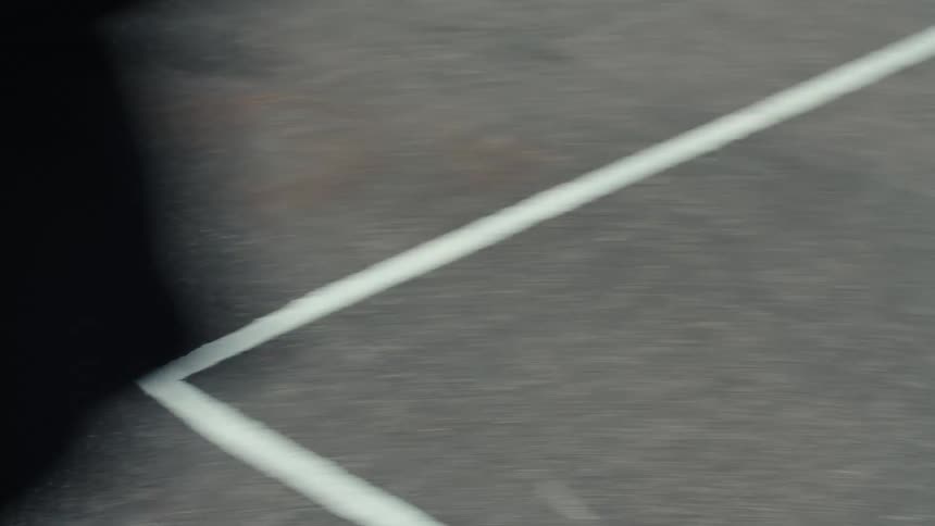 A young man rides a bicycle on an asphalt sport court