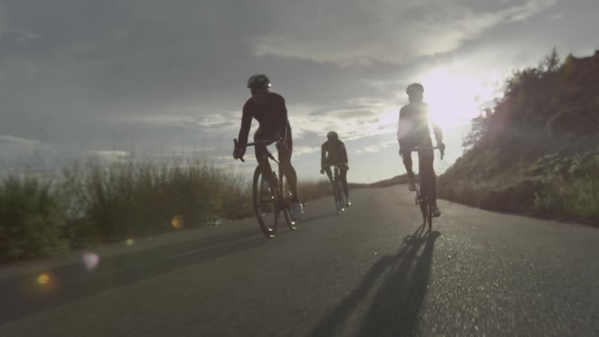 A few bicyclists riding down a country road at dusk
