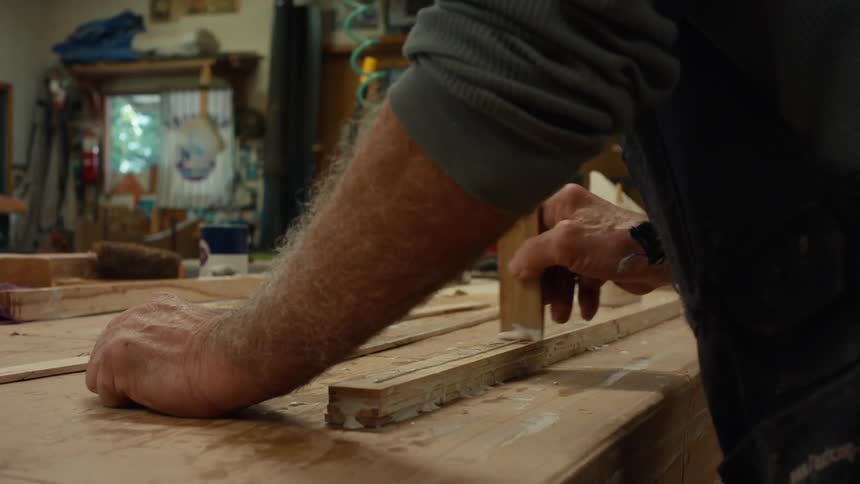 Hands of a male carpenter applying glue to a piece of wood on a table