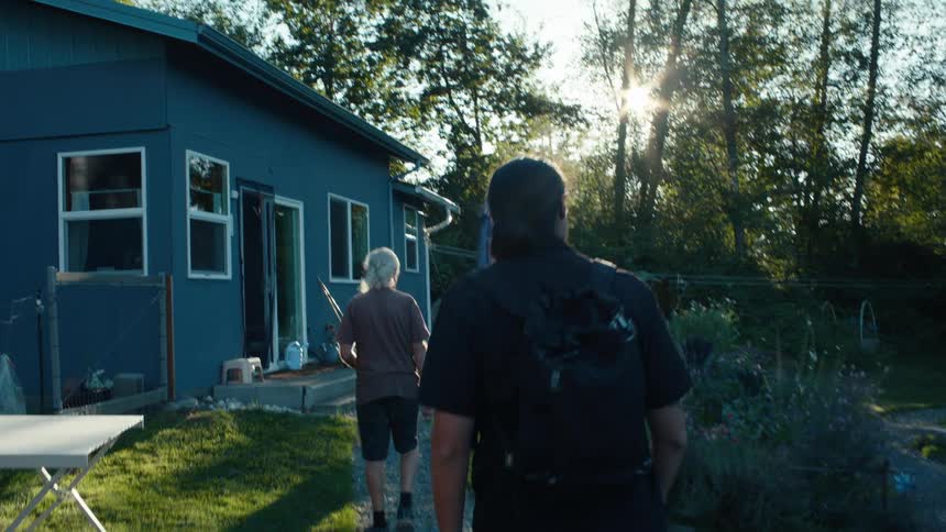 Two people walk through the yard and enter the house