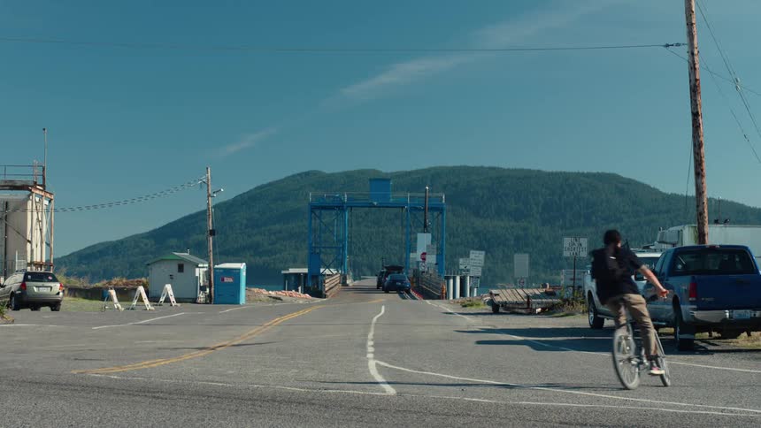 Man riding a bicycle turns left to the bridge leading to the mountain