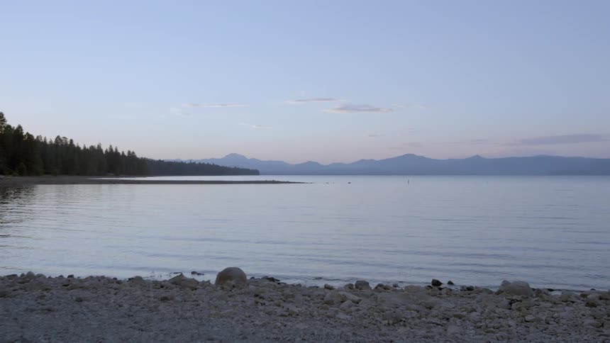 A view of a lake with trees and mountains in the background