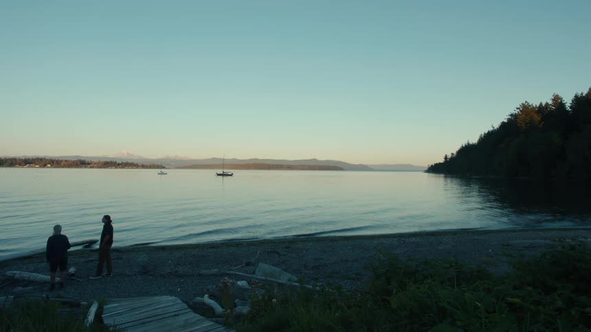 Two people standing talking by the lake