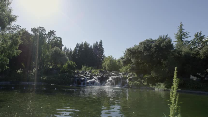 A small waterfall on the side of a quiet lake