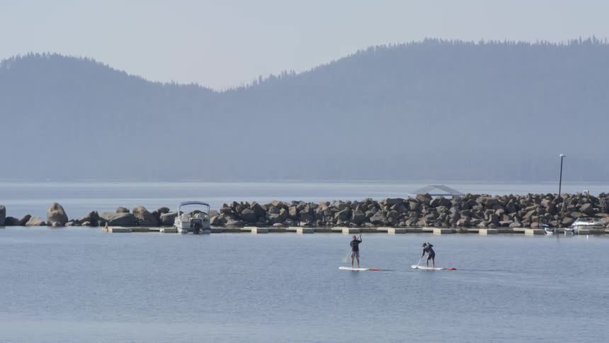 Two men paddle board on the water