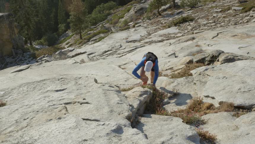 Man climbs up steep rocky terrain