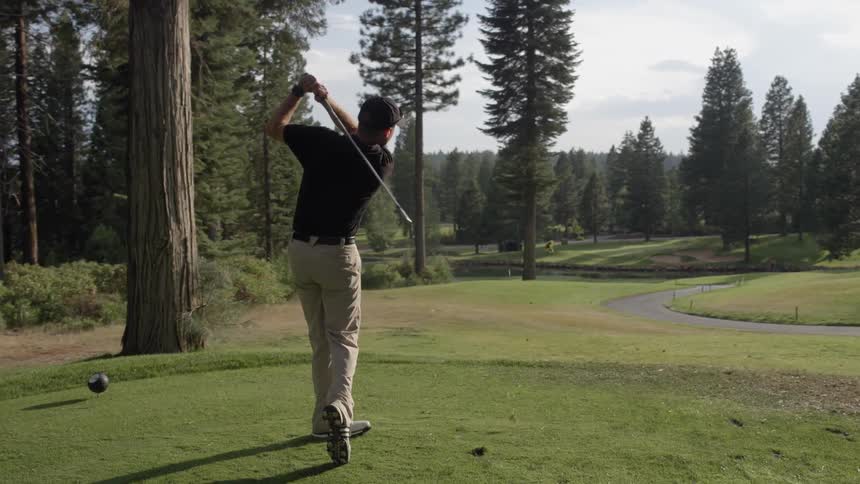 A golfer swings and drives the ball