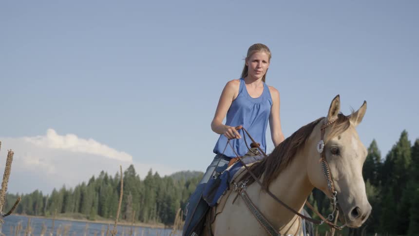Several people are riding horses in the mountains next to a lake