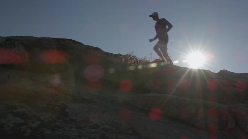 A man jogs along a cliff side as the sun shines
