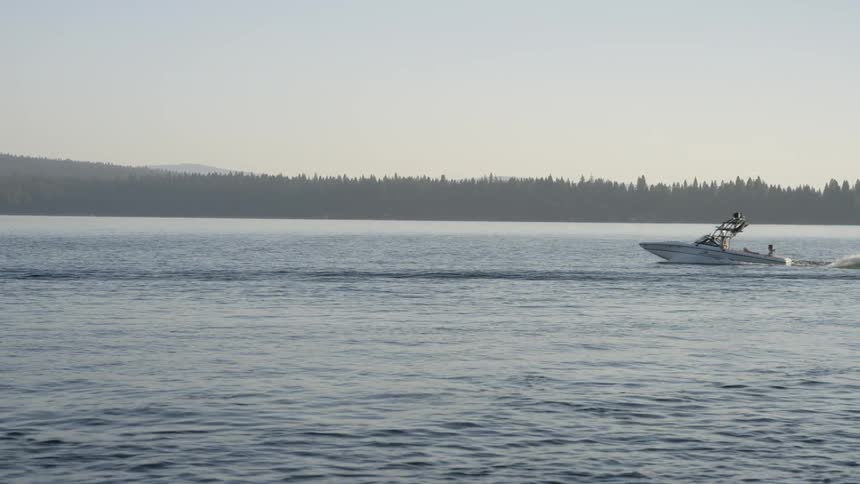 A boat rides on a lake on a sunny day
