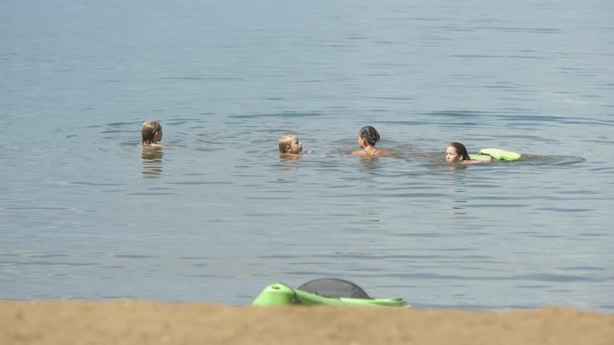 A group of kids swimming in a lake or pond