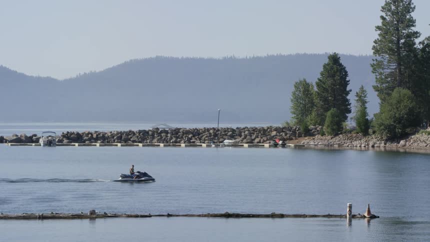 A person on a jet ski riding in a canal or waterway next to some rocks