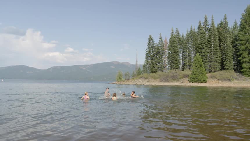 Group of people splashing around in a large lake on a partly cloudy day