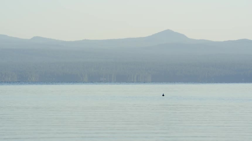 A person in a boat on a lake with mountains in the distances