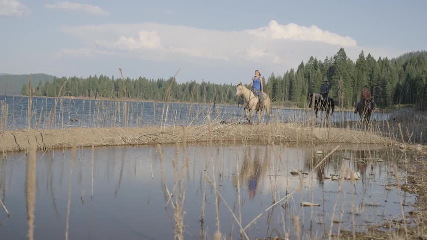 A woman riding a horse on some land in between waterways
