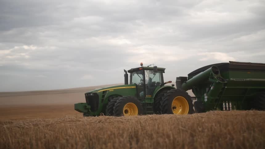 A tractor is driving across the crops
