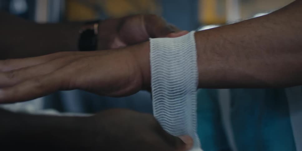 A man wrapping another mans wrist with a bandage