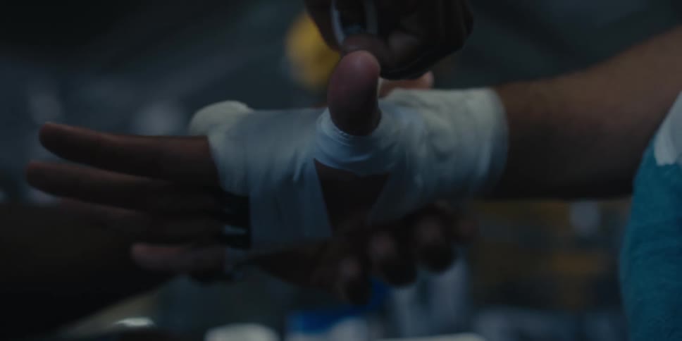White tape being placed on the hand and wrist of a male boxer