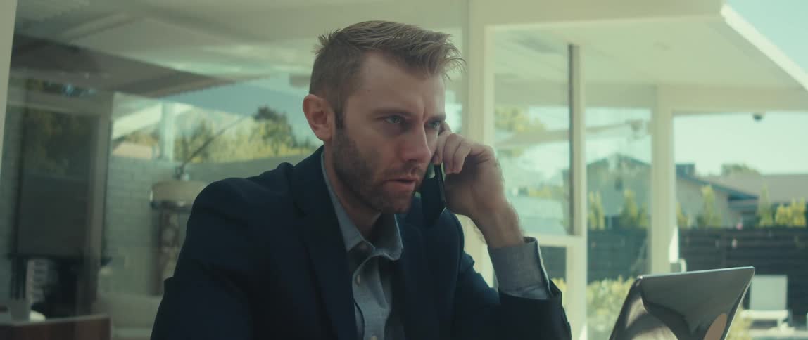 Man talking on a phone call while sitting in front of an open laptop