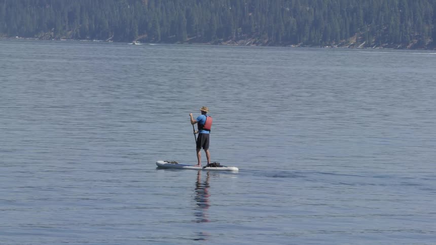 A man is paddle-boarding on calm waters
