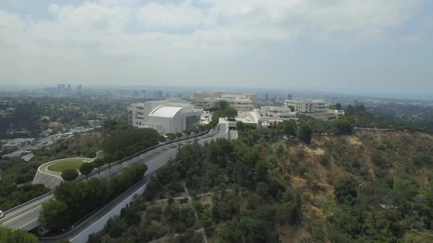 A tram is making its way up a hill toward a large building complex