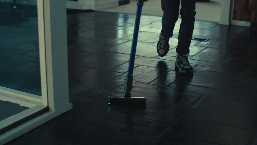 A man is singing and dances as he vacuums