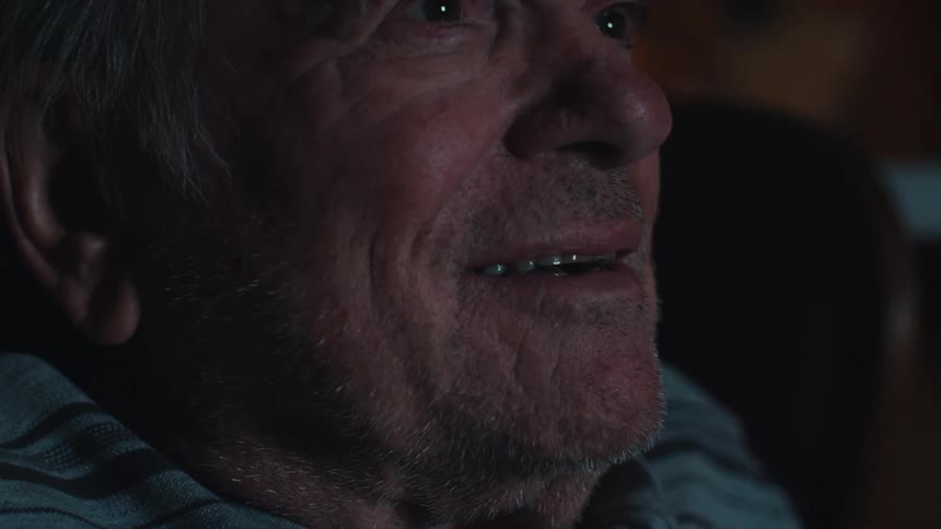 Portrait of an elderly man sitting in an armchair watching