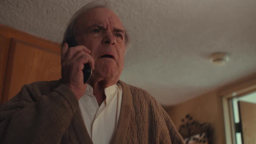 Elderly man standing with sad facial expression while on a phone call