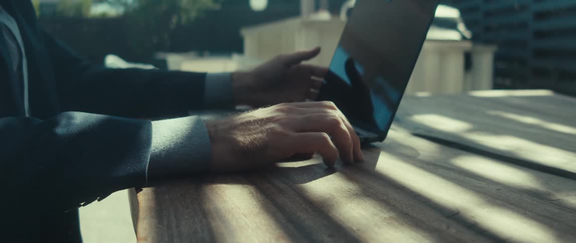 Hands of a man typing on a laptop that is open on the table