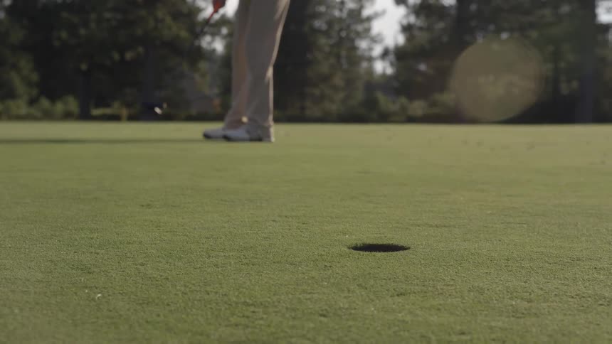 Person hits a golf ball into a hole