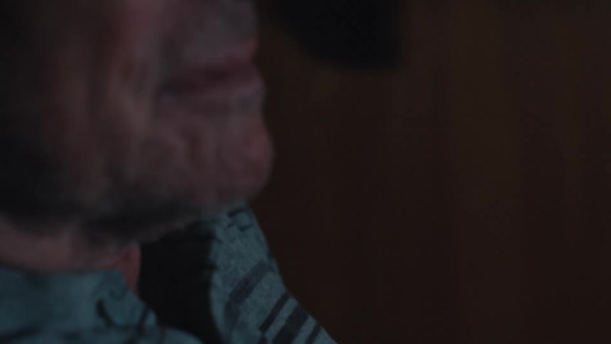 The face of an elderly man who is sitting in a chair with his hand on the side of the chair he is staring straight ahead