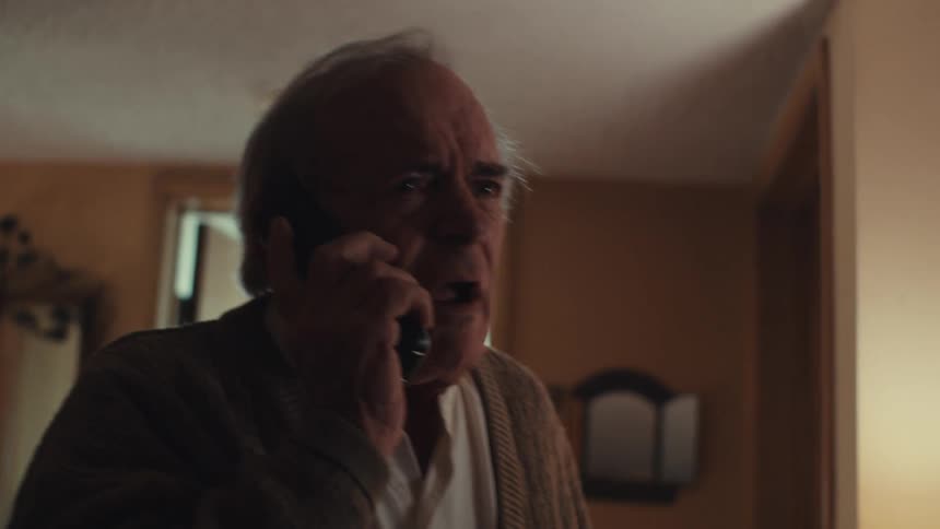 Portrait of an elderly man on a phone call with a scared facial expression