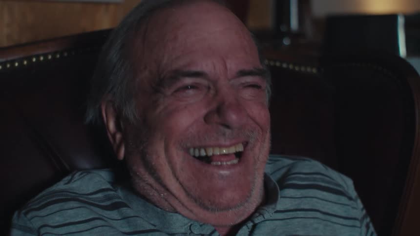 Portrait of an elderly man sitting watching and laughing