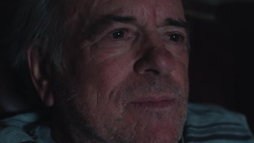 Closeup of an elderly man watching television in a dimly lit room