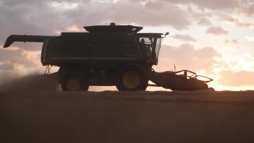 Combine harvester in action across a field at sunrise