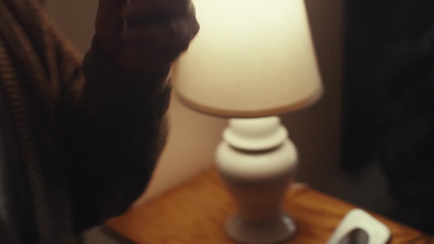 An elderly man gets a call on a cordless phone and smiles as he answers it