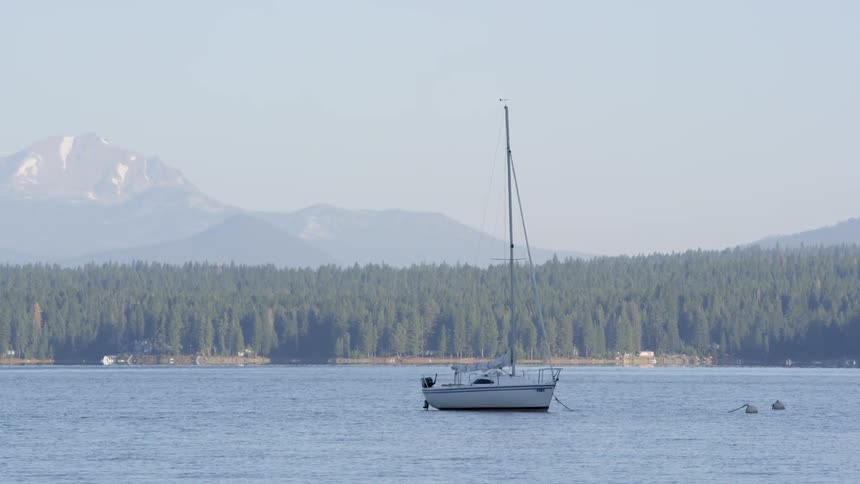 Sailboat sitting with no sail on calm waters on a clear day