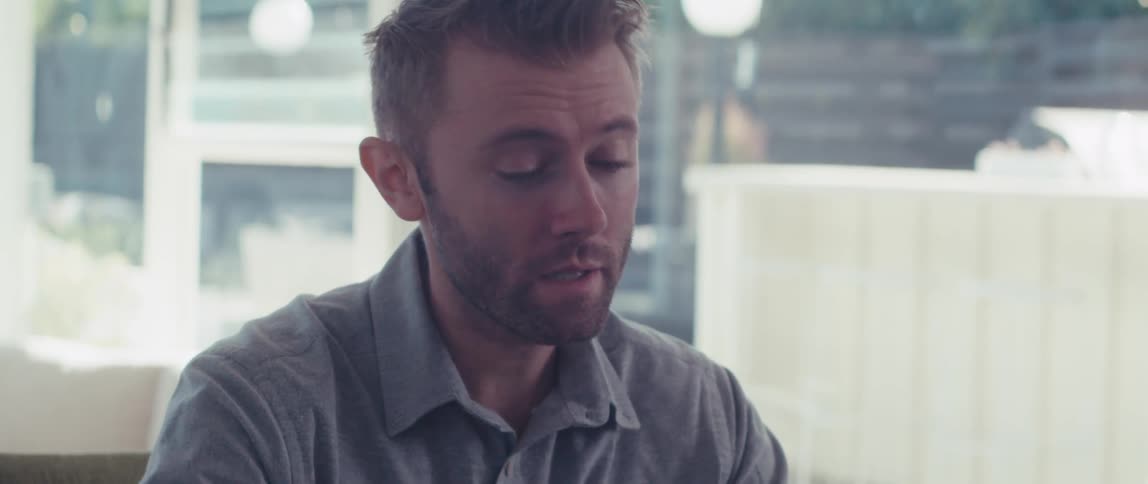 Man sitting indoors and interacting with a laptop