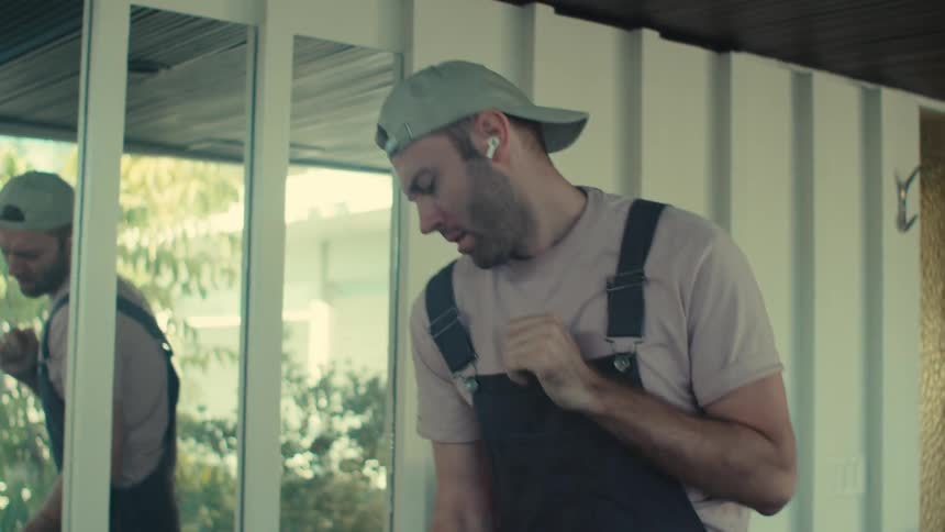 A janitor dances to music in his earbuds while cleaning an office