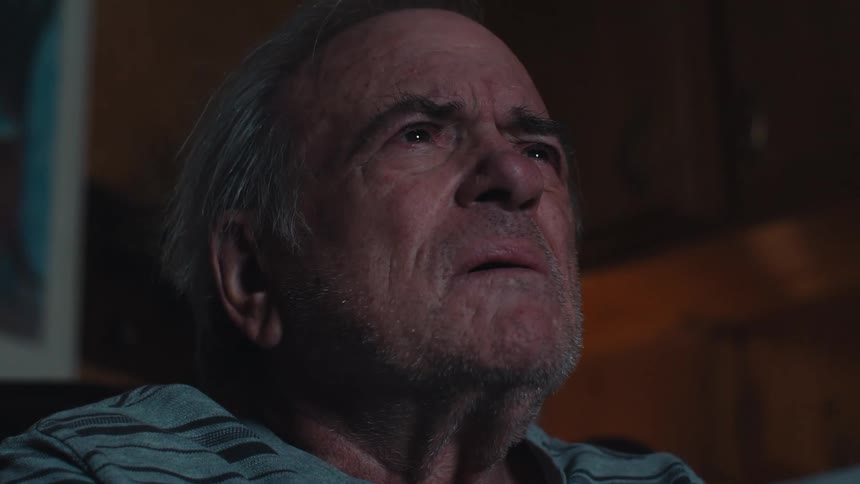 Close up of a confused elderly man watching tv at night