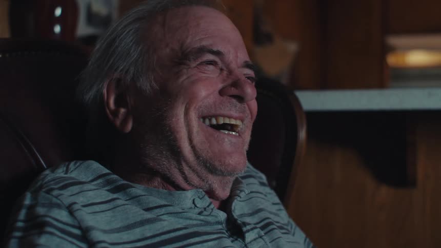 Elderly man sitting in an armchair laughing
