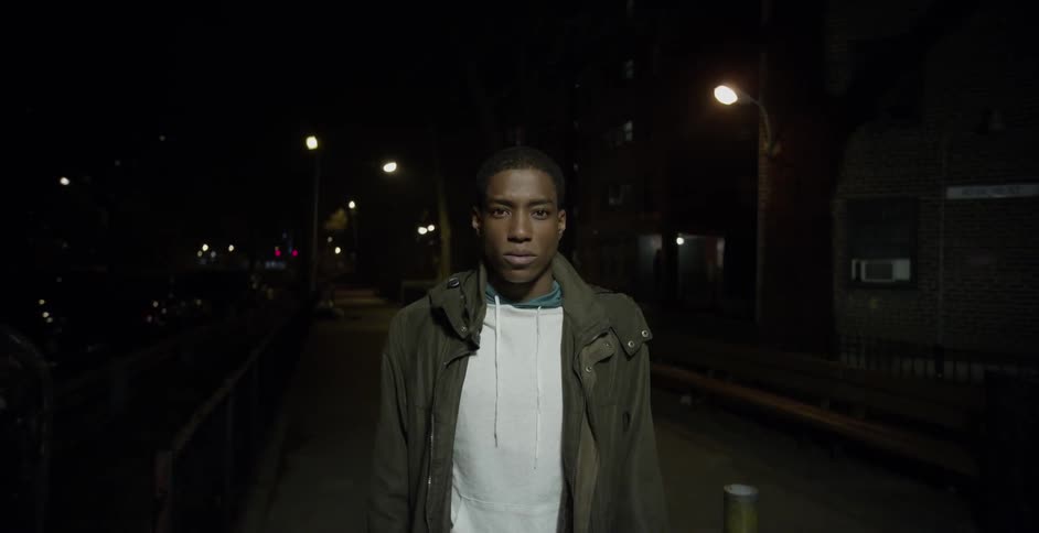 Man with a white shirt standing on a city street at night