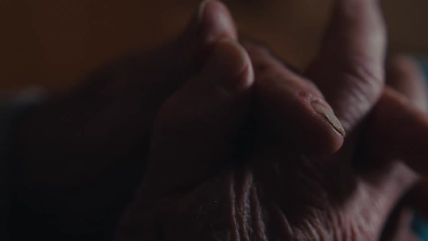Close up of an elderly persons hands clasped together