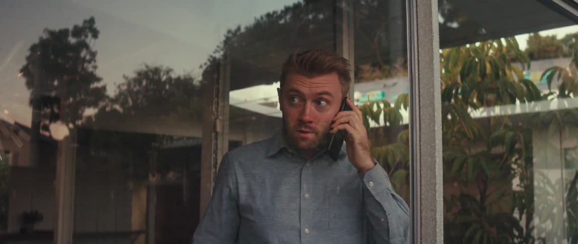A man is talking on his phone by the window